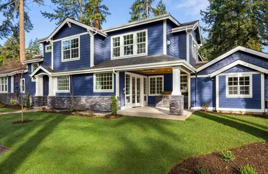 A blue house with white trim and green grass.