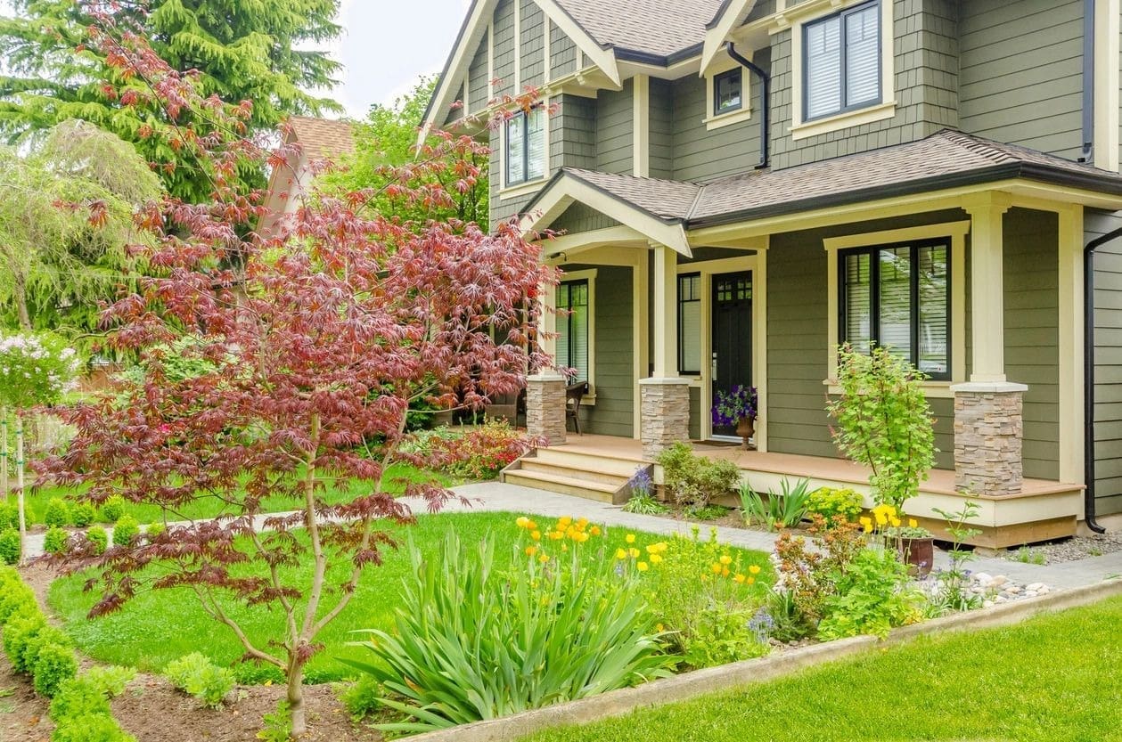 A house with flowers and trees in front of it.