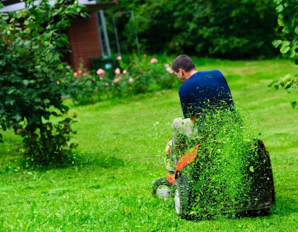 A man is cutting grass with an electric saw.