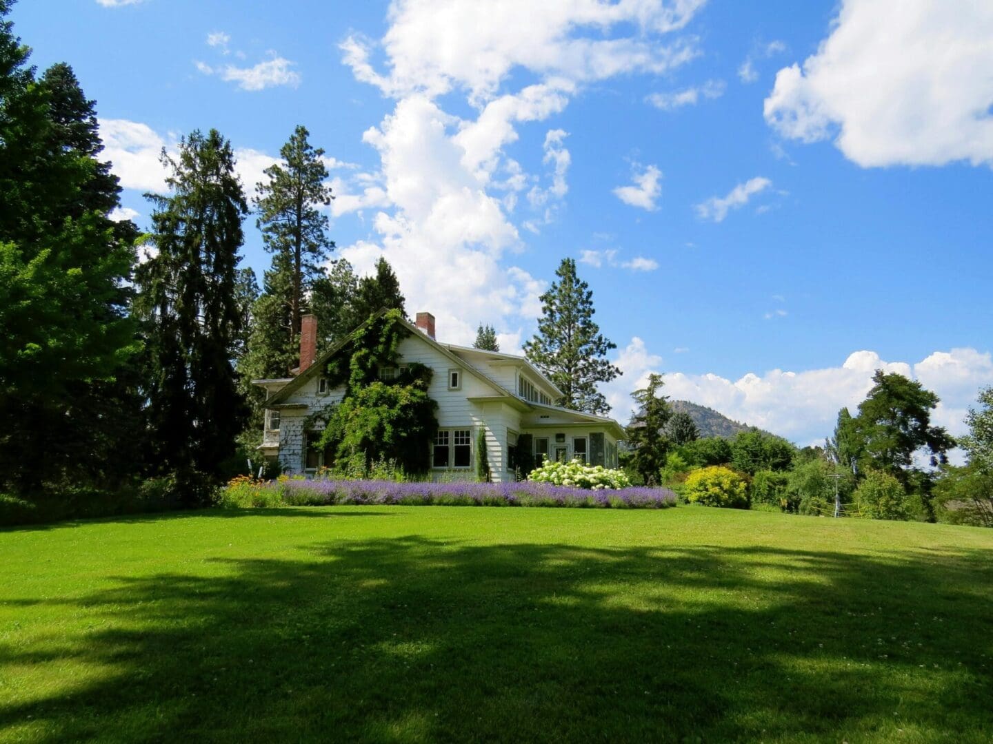 A large white house sitting in the middle of a green field.