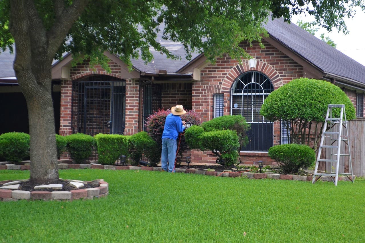 A man in blue jacket holding an umbrella near a house.